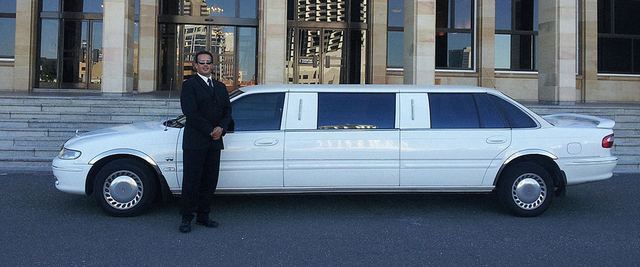 Chauffeur standing beside a white stretch limousine